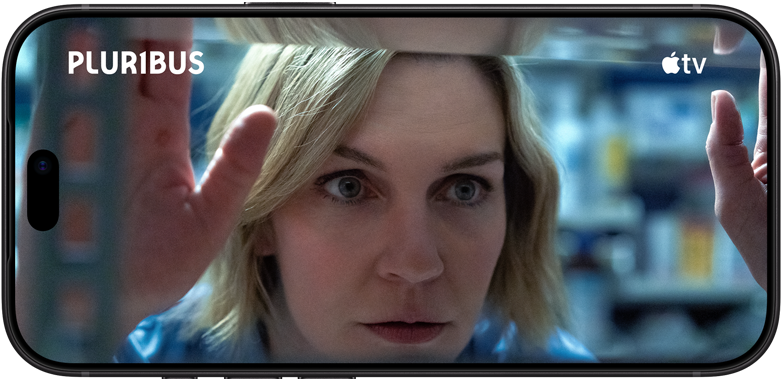  iPhone 18 Pro, โหมดแนวนอน, แสดงภาพระยะใกล้ของผู้หญิงที่กำลังมองผ่านหน้าต่าง ชื่อซีรีส์: Pluribus