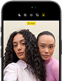 iPhone 18 Pro, สีดำ, ภายนอกด้านหน้า, แสดงให้เห็นสองคนกำลังโพสท่าให้กล้องเพื่อสาธิตกล้องหน้า Center Stage