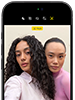 iPhone 18 Pro, สีดำ, ภายนอกด้านหน้า, แสดงให้เห็นสองคนกำลังโพสท่าให้กล้องเพื่อสาธิตกล้องหน้า Center Stage