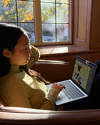 บุคคลหนึ่งนั่งอยู่บนเก้าอี้และกำลังใช้ MacBook Air